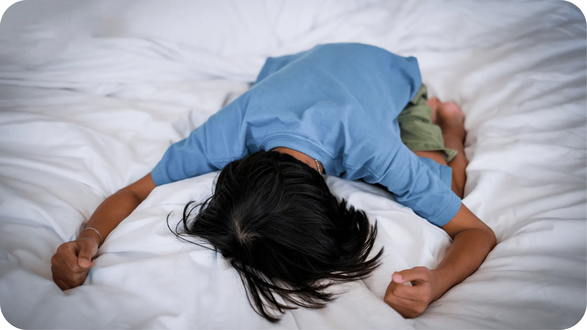 An upset child face down on their bed.